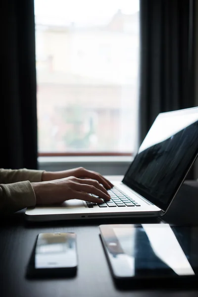Γυναίκα χρησιμοποιώντας ένα φορητό υπολογιστή δίπλα σε ένα παράθυρο με το tablet pc και smartph — Φωτογραφία Αρχείου