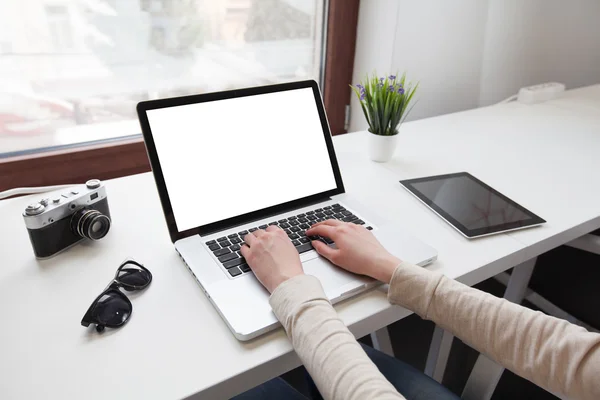 Vrouw met behulp van een laptop naast een venster met de tablet pc naast haar — Stockfoto