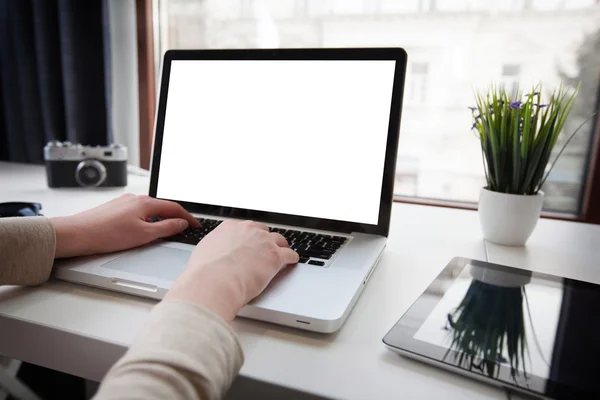 Vrouw werkt op de computer voor een raam met tablet naast — Stockfoto