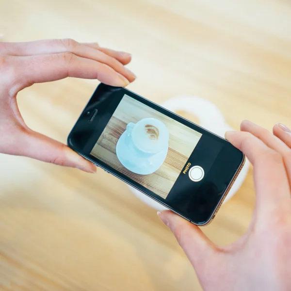 Kvinna tar en bild av en kaffekopp med hennes smarta telefonen — Stockfoto