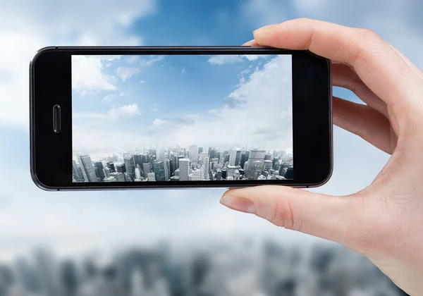 Женщина рука делает фото города со смартфоном — стоковое фото