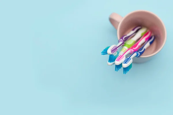 Close-up of four multi-colored toothbrushes in a cup holder against a blue background with copy space, top view. The concept of healthy teeth in the family — Stock Photo, Image