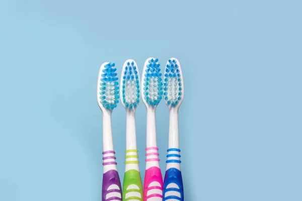 Photo de quatre brosses à dents multicolores, fond bleu avec espace de copie, vue du dessus. Le concept de dents saines dans la famille, soins dentaires. — Photo