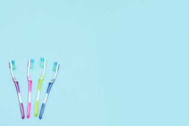 Dört diş fırçası seti ve fotokopi alanı. Renkli bir grup diş fırçası. Boşluğu metin için kopyala. Mavi arka planda düz uzandı