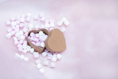 Tekstil arka planında, kalp şeklinde bir hediye kutusunda pembe şekerlemeler mevcut, tatlım. Sevgililer Günü. Uzayı kopyala Fotoğraf..