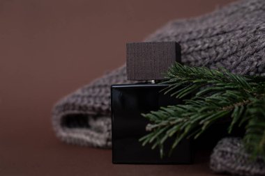 Parfüm, erkek parfümü ya da tıraş sonrası esmer arka planda erkek kazağı ve iğnelerinin yanında tıraş losyonu. Lüks, Hediye. Bir parfüm dükkanının reklamını yapmak için yakın plan fotoğraf, blog