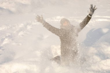 Sinematik defoktus düşen kar taneleriyle yakalanır. Mutlu çocuk kışın kar yığınlarında oynuyor. Kahkaha ve neşe