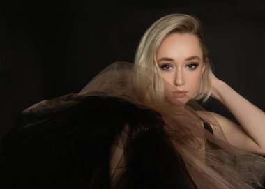 Siyah arka planda, organzaya sarılı sarışın bir kadının güzel portresi. Şık kısa saç stili. Stüdyo kısa, kopyalama alanı