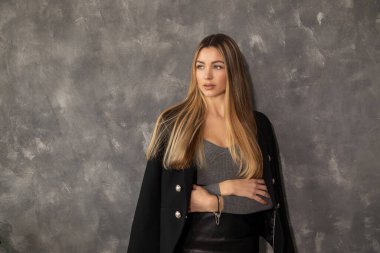 Çekici sarışın kadın, kentin beton duvarına yaslanmış fotokopi alanının yanında yer almaya çalışıyor.