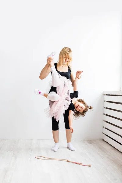 Donna mamma indulge nella danza con la sua piccola figlia, è impegnata in ginnastica in interni bianchi, foto di stile di vita a casa o in studio di danza, sogno dei bambini — Foto Stock