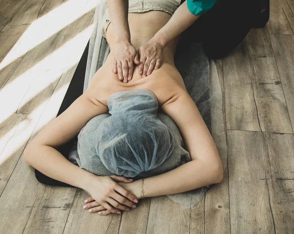 ホテルの木製の床で専門家による指圧マッサージを持っている認識できない女性 — ストック写真