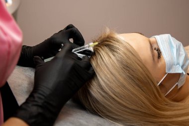 Woman getting injection into scalp, mesotherapy, hair loss therapy. Doctors wearing gloves in salon making medical manipulations to patient. Close-up photo clipart