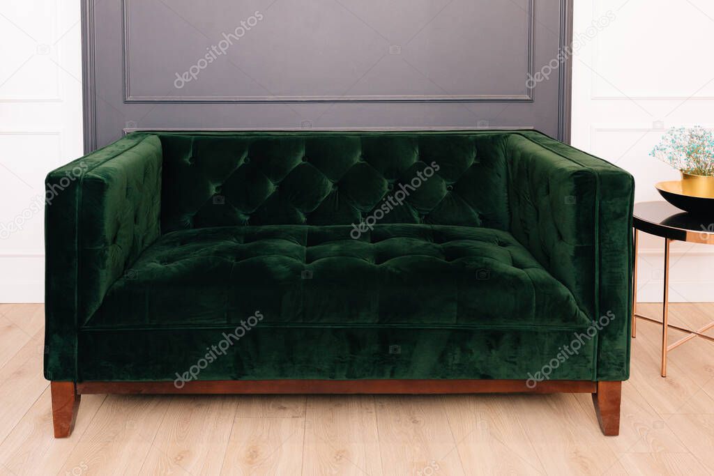 Dark green malachite velor sofa in the interior. Capitone textile, suede, velour, with buttons