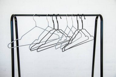 Paslanmaz çelik giysi tırabzanı beyaz bir duvara karşı boş kaplamalı, kısmen kapalı.