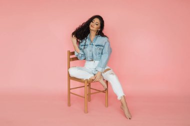 Güzellik ve saç bakım konsepti. Pembe arka planda uzun kıvırcık saçlı esmer kadın, stüdyo fotoğrafı.