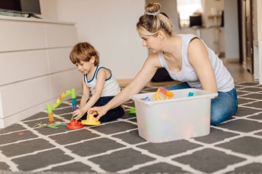 Annem 3 yaşında bir çocukla yerde otururken oynuyor. Anne-oğul ilişkisi. Tasarım becerilerinin geliştirilmesi ve eğitilmesi.
