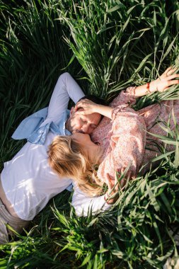 Genç çift güneşli bir günde çayırda piknik yapıyor. Erkek ve kadın birlikte olmaktan hoşlanırlar.