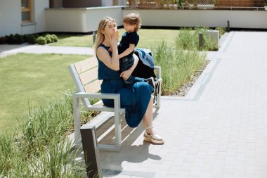 Bekar bir anne, 3 yaşındaki oğlu kollarında bankta oturuyor. Çocuklar için samimiyet ve sevgi kavramı.