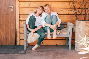 İki olgun kadın ahşap evin yanındaki bankta oturur ve zor bir günün ardından dinlenir, hayat tarzı fotoğrafı.