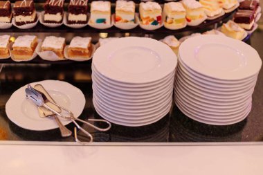 Çeşitli tatlılar için iki yığın beyaz tabak misafirler için hazırdır. Otelde kahvaltı. Bayram etkinliği. Tatlı büfe. Dinlen ve seyahat et. Tat ve zevk. 