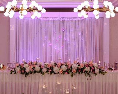 Lüks çiçek çelenkleriyle süslenmiş merkez düğün masası kutlamanın başlamasını bekliyor. Düğün organizasyonları. Çiçekçilik ve tasarım. Pembe tonlar. Kutlama ve zevk. Eğlence ve eğlence.. 