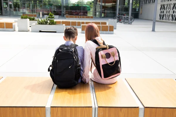 Skolbarn Flicka Och Pojke Sitter Med Skolryggsäckar Träbänk Bland Betongväggar — Stockfoto