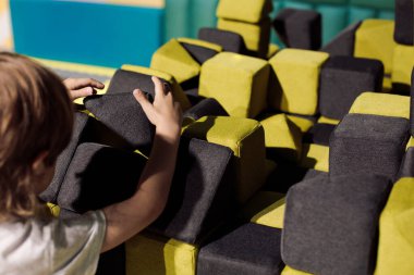 Little boy builds from soft blocks in children's scientific and educational center. Problems with communications. Educational toys. Organization of game zones. Children's development centers.