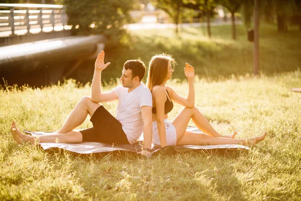 年轻夫妇一起做运动 在城市草坪上做瑜伽 夏夜在一起 — 图库照片