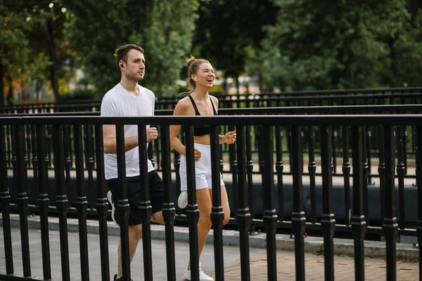 Young couple running in the city park, joint sports, cheerfulness, city lifestyle — Fotografia de Stock