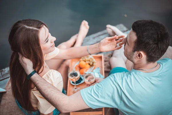 川や湖の近くのピクニックで若いカップルの後部ビュー 一緒に屋外でワインを飲む女性と男性 夏休みの楽しみを持っている人々 — ストック写真