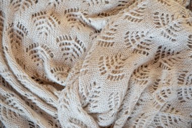 Örgü örülmüş, bej desenli battaniye eşarbı, yakın çekim fotoğraf, tam çerçeve, üst görüş. Doğal yün ve pamuktan oluşan harika bir arka plan. Yüksek kalite matireal