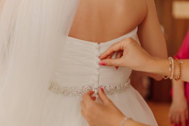 Düğmesiz eller nedimeler gelinliklerini bağlar. Gelin konsepti önemli bir gün için toplanıyor, düğün kutlaması. Yüksek kalite fotoğraf