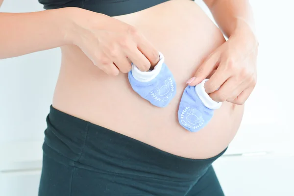 Pregnant woman with little blue socks — Stock Photo, Image