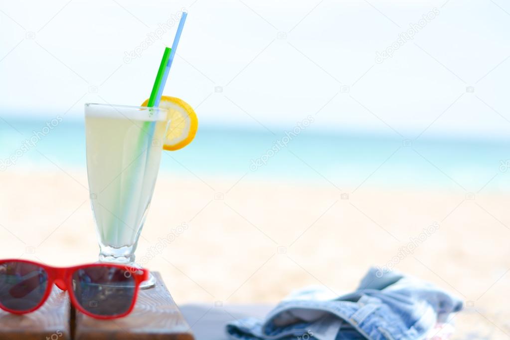 cocktail glass and sunglasses on ocean beach 