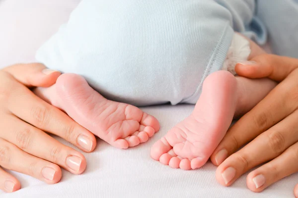 Female hands and cute feet of newborn — Stock Photo, Image