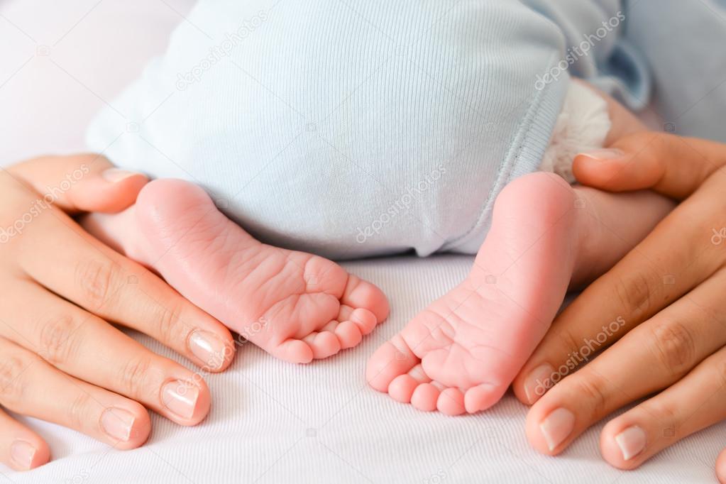 female hands and cute feet of newborn 