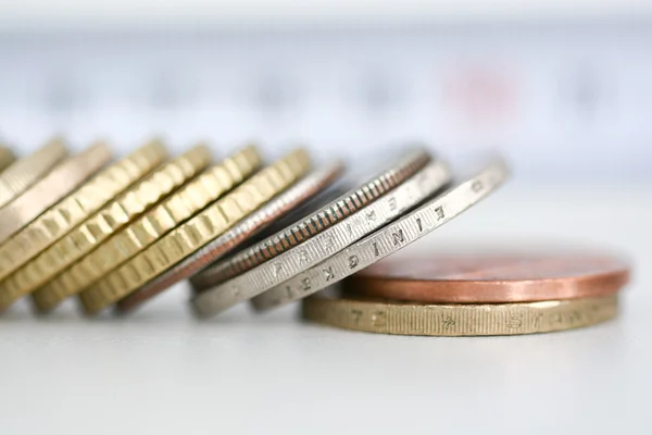 Row of tilted coins on white table — Stock Photo, Image
