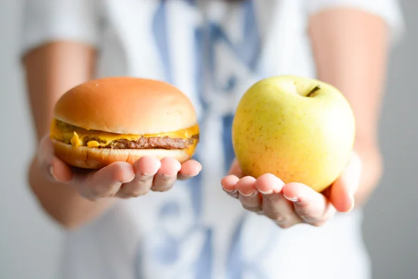 female holding hamburger and apple