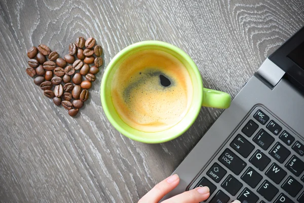 Šálek kávy s notebookem a srdcem z fazolí — Stock fotografie