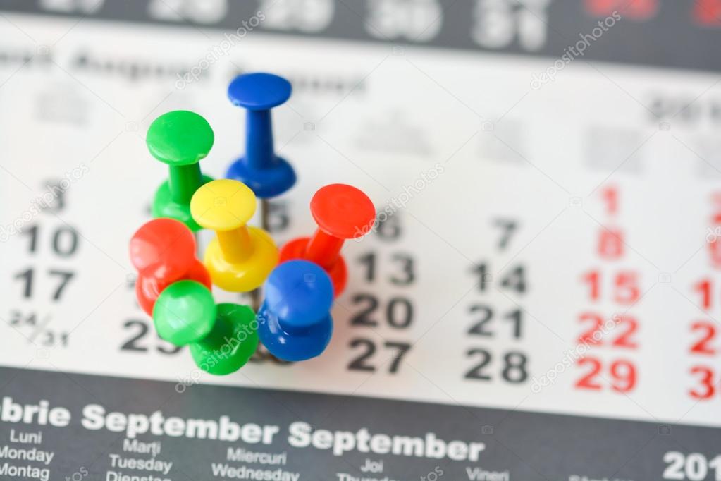 colorful drawing pins on calendar sheet 