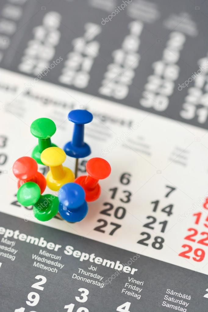 colorful drawing pins on calendar sheet 