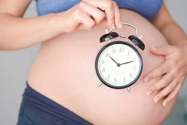 Mujer embarazada sosteniendo reloj — Foto de Stock