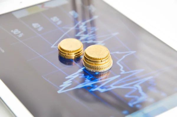 Columns of coins on screen of tablet — Stock Photo, Image