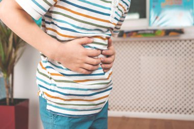 Çocuk evde ellerini karnına koyuyor. Bir çocukta karın ağrısı. Çocuklarda zehirlenme