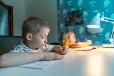 Çocuklar evde yazım yapıyorlar. Çocuklar yazmayı öğrenir. Evde eğitim görmüş çocuk ödevlerini yapıyor.