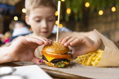 Kafedeki bir çocuk mini burger ve patates kızartması yer. çocuk menüsü