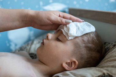 Yüksek ateşi olan bir çocuk yatakta yatıyor. Çocuğun yüksek ateşi var. Bir anne hasta bir çocuğa bakar. Çocuğun ateşi var.