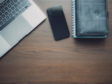 Laptop ve akıllı telefon ahşap masada. Açık dizüstü bilgisayarı ve ahşap masa üzerinde kopyalama alanı olan akıllı telefonu olan en düşük iş yeri.