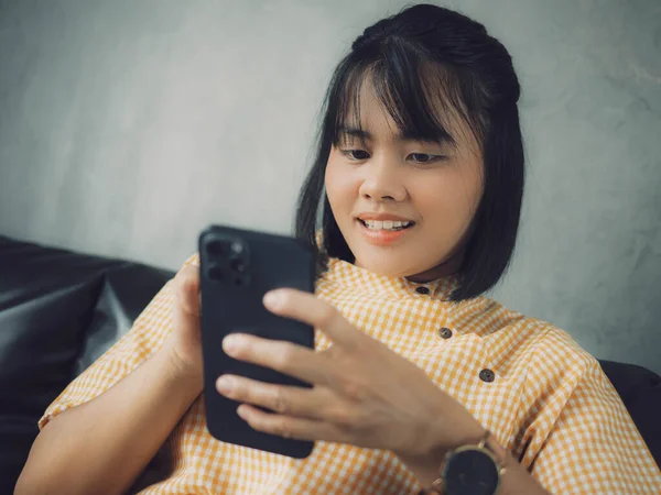 Akıllı telefon kullanan bir kadın, rahat bir evde oturan genç bir hippi kız ve modern akıllı telefon cihazı kullanan, elinde siyah bir dokunmatik telefon tutan bir kadın. Sosyal ağ oluşturma kavramı.