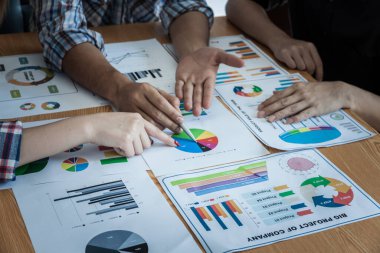 İşletme ekibi, beyin saptırıcı toplantı sürecinde çalışıyor. İş adamları başarılı takım çalışmalarının sonuçlarını gösteren çizelge ve grafikleri tartışıyor.